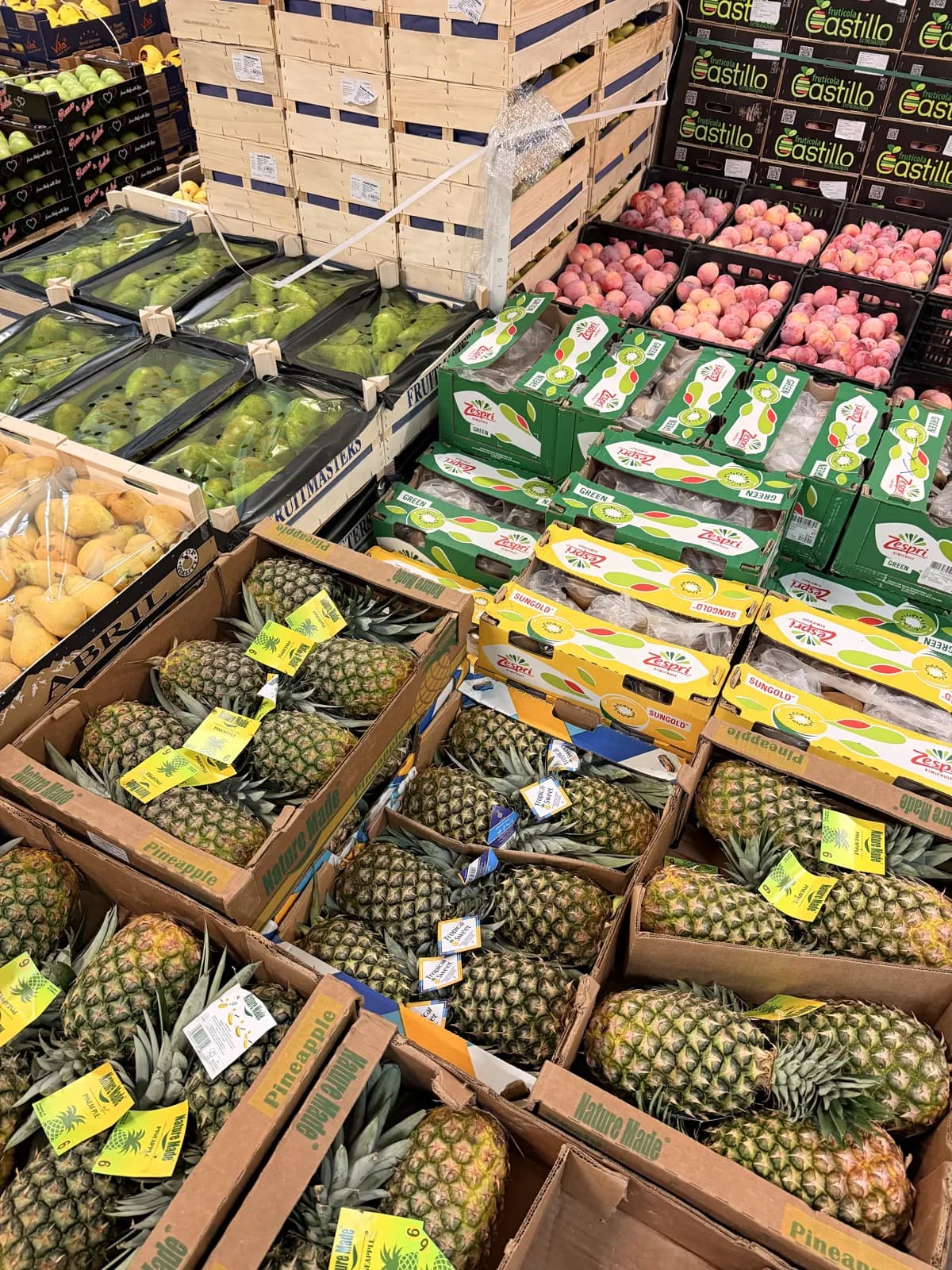 Ananasy, kiwi Zespri Green i SunGold oraz śliwki na hali magazynowej